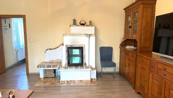 Gemütliches Wohnzimmer mit traditionellem Kachelofen, Holzboden und rustikalen Möbeln.