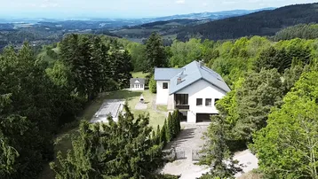 Weitläufige Luftaufnahme des Anwesens mit Haupthaus, Nebengebäude und Panoramablick über die Landschaft.