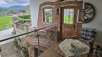 Gemütlicher Balkon mit rustikalen Ziegelwänden, Holztisch und Stühlen, bietet Bergblick.