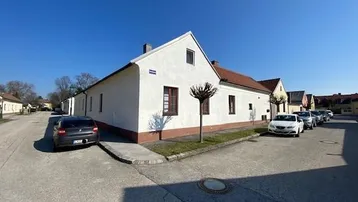 Ländliches Einfamilienhaus mit weißer Fassade und traditionellem Ziegeldach unter blauem Himmel.