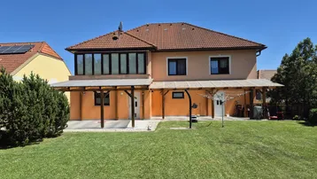 Großzügiger Gartenbereich hinter dem Haus mit überdachter Terrasse und Wintergarten im Obergeschoss.