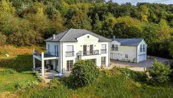 Großzügiges Einfamilienhaus mit mehreren Balkonen und umgeben von viel Grün.