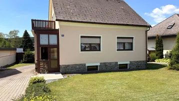Vorderansicht des Hauses mit gepflegtem Rasen, Vorgarten und einem sonnigen Eingangsbereich.