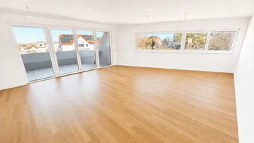 Helles Wohnzimmer mit Holzboden, großen Fenstern und Zugang zu einem Balkon.