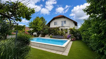 Schönes Einfamilienhaus mit großem Garten und privatem Pool unter blauem Himmel.