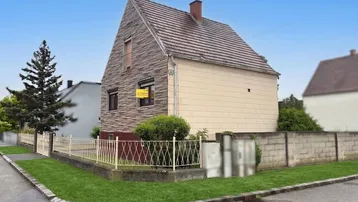 Rückwärtige Seitenansicht des Hauses von der Straßenecke mit angrenzendem Zaun und Nachbargebäuden.