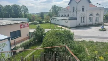 Weitblick über eine grüne Landschaft mit einem historischen Gebäude im Hintergrund unter blauem Himmel.