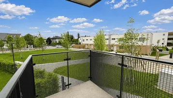 Balkon mit Metallgeländer und Blick auf die grüne Wohnanlage und umliegende Gebäude.