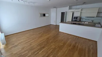 Heller offener Wohnbereich mit Holzboden und integrierter Küche, ideal für modernes Wohnen.