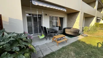 Gemütliche Terrasse mit Gartenmöbeln, Schaukel und aufblasbarem Whirlpool im Freien.
