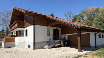 Gepflegtes Haus mit Satteldach, Holzverkleidung, Doppelgarage und Carport im Freien.