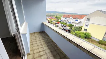 Balkon mit Fliesenboden und weitem Blick über die umliegende Wohngegend und Landschaft.