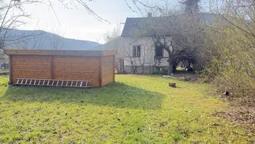 Großer Gartenbereich mit Rasenfläche, einem Holzschuppen und Blick auf die umliegende Landschaft.