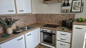 Moderne Küche mit weißen Schränken, Holzarbeitsplatten und gemusterter Rückwand.