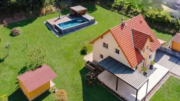 Luftaufnahme des Hauses mit großem Garten, Swimmingpool und überdachtem Sitzbereich.