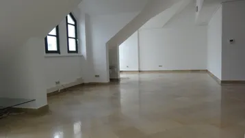 Geräumiger Wohnbereich mit schrägen Wänden, Dachfenstern und hellen Fliesenböden, der viel natürliches Licht erhält.