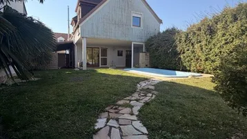 Großzügiger Gartenbereich mit Rasenfläche, Steinpfad und kleinem Pool hinter dem Haus.