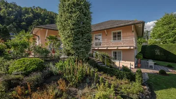 Charmantes Haus mit gepflegtem Garten und üppiger Bepflanzung unter blauem Himmel.