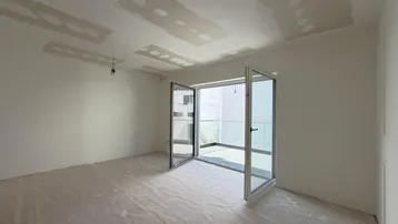 Unfertiges Zimmer mit großen Fenstertüren und Zugang zu einem französischen Balkon.