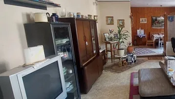 Geräumiges Wohnzimmer mit Fliesenboden, traditionellen Möbeln und Blick in den Essbereich.