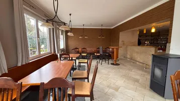 Geräumiger Gastraum mit Holztischen, Bänken und Fliesenboden, ideal für ein Restaurant oder Café.