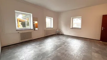 Heller, unmöblierter Raum mit drei Fenstern und strapazierfähigem Laminatboden, ideal für vielfältige Nutzung.
