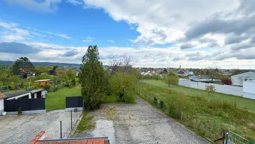 Weitläufiger Blick über die Umgebung mit viel Grün, Häusern und einem Dorf in der Ferne.