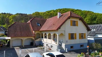 Großzügiges Einfamilienhaus mit Doppelgarage, rotem Ziegeldach und umgebender Natur.