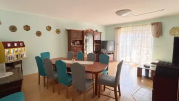 Geräumiger Wohn-Essbereich mit Holzboden, großem Esstisch und Zugang zum Garten.