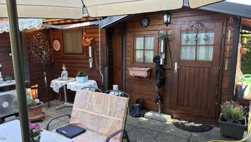 Gemütliche Terrasse mit Holzhütte, Sonnenschirm und Sitzgelegenheiten für entspannte Stunden im Freien.