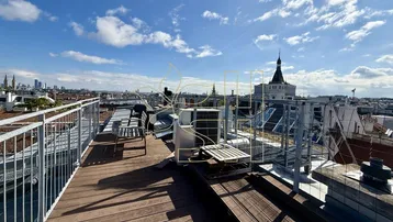 Geräumige Dachterrasse mit Holzboden, Sitzgelegenheiten und weitem Blick über die Stadt.