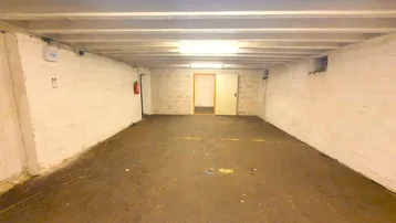 Geräumiger Kellerraum mit einfacher Beleuchtung und unverputzten Wänden, ideal als Lagerfläche.