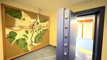 Eingangsbereich eines Tresorraums mit einer großen Karte an der Wand und einer geöffneten Tresortür.
