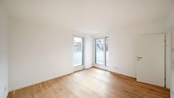 Helles Schlafzimmer mit Holzboden und zwei Fenstern, die Zugang zu einem französischen Balkon bieten.