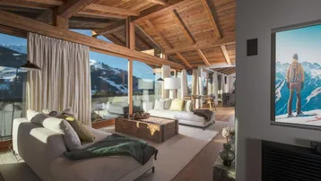 Gemütliches Wohnzimmer mit hohen Holzdecken, großen Fenstern und Panoramablick auf die verschneiten Berge.