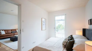 Gemütliches Schlafzimmer mit Doppelbett, Teppichboden und französischem Balkon.