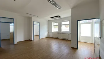 Geräumiger, heller Büroraum mit Holzfußboden und mehreren Türen, bereit zur individuellen Gestaltung.