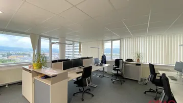 Helles Großraumbüro mit mehreren modernen Arbeitsplätzen, großen Fenstern und weitem Stadt- und Bergblick.