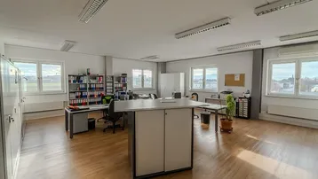 Großes, helles Büro mit mehreren Arbeitsplätzen, Holzfußboden und weitem Blick ins Grüne.