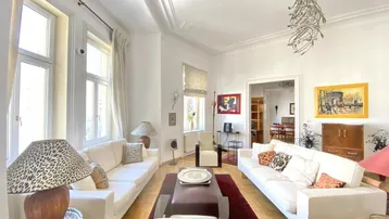 Helles Wohnzimmer mit hohen Decken, Stuckverzierungen und elegantem Parkettboden.