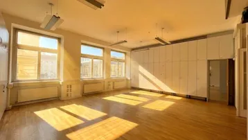 Großes, helles Zimmer mit Holzboden und vielen Fenstern, ideal für Büro oder Gewerbe.