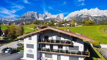 Modernes Apartmenthaus in alpiner Landschaft mit Balkonen und majestätischem Bergblick.