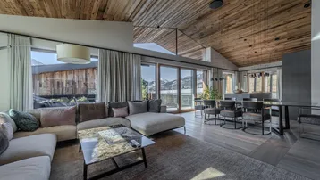 Heller Wohn- und Essbereich mit Holzbalkendecke, bequemer Couch und Zugang zur Terrasse.