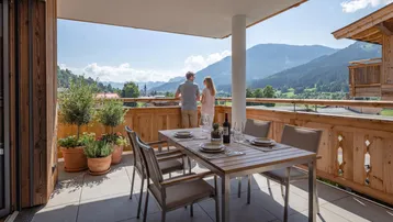 Geräumiger Balkon mit Esstisch, Pflanzen und Panoramablick auf die Berge und das Tal.