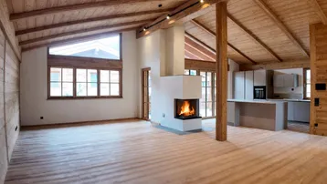 Geräumiger offener Wohnbereich mit Holzbalkendecke, Kamin und integrierter Küche, ideal für geselliges Beisammensein.