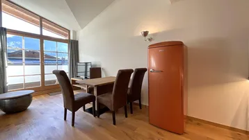Heller Essbereich mit Holztisch, retro Kühlschrank und großen Fenstern mit Bergblick.