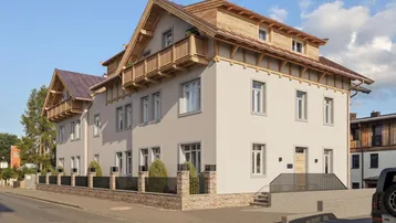 Modernes Mehrfamilienhaus mit traditionellen Holzbalkonen und heller Fassade.