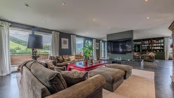 Geräumiges Wohnzimmer mit großen Fenstern, Bergblick und stilvoller Einrichtung.