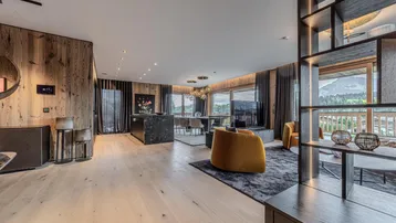 Modernes, offenes Wohnzimmer mit Holzwänden, Bergblick und stilvollen Möbeln sowie Zugang zum Balkon.