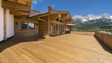 Große Holzterrasse mit traditionellem Chalet-Stil Gebäude und beeindruckendem Bergblick.